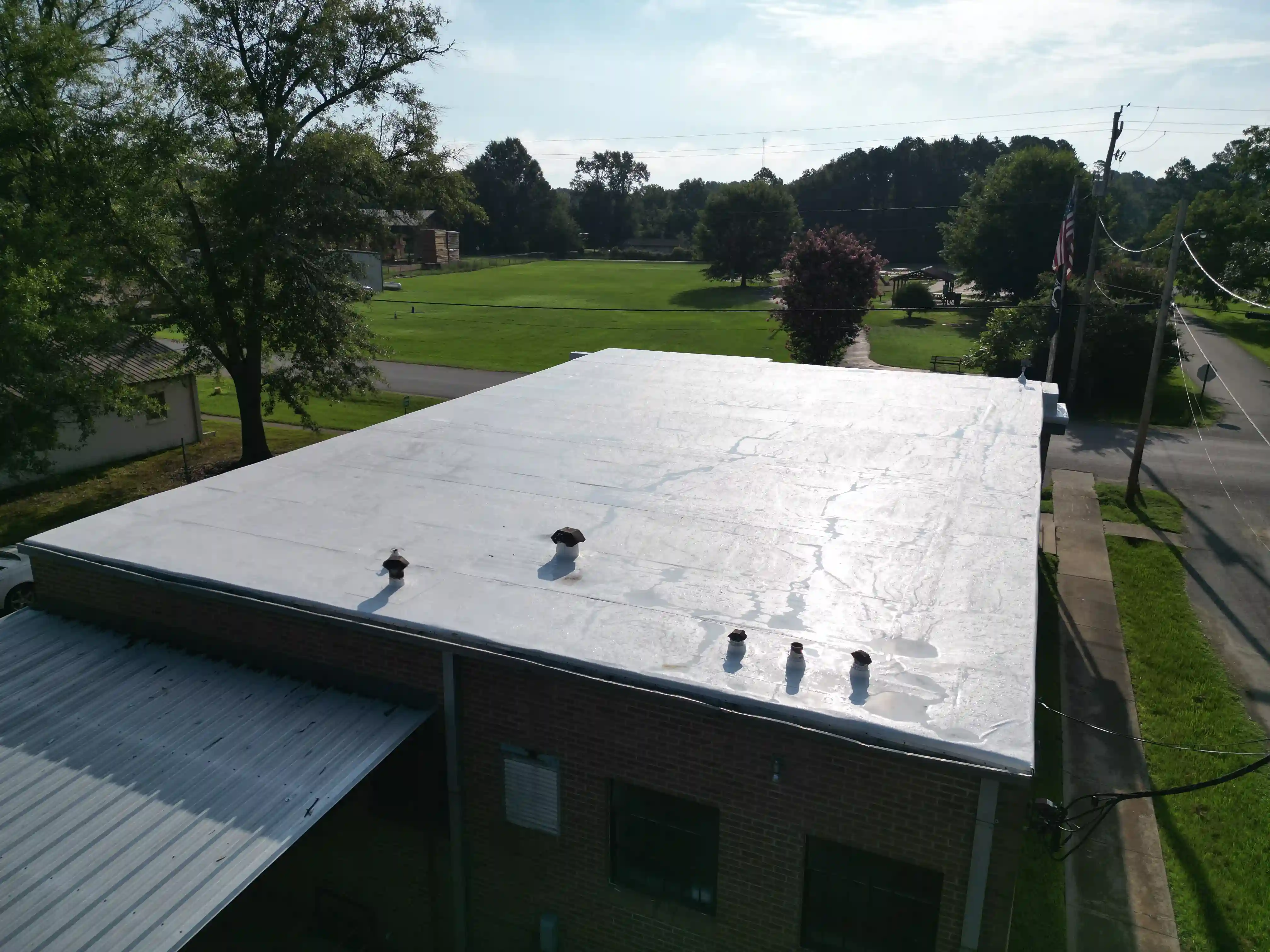 Small-town brick storefront building topped with a finished white membrane roof